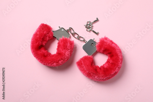 Red furry handcuffs and keys on pink background, top view. Sex toy photo