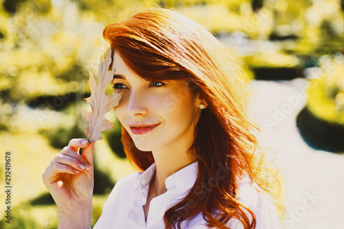 Autumn woman with autumnal mood. Autumn Beauty. Outdoor portrait Gorgeous model girl with sunny day light. Beautiful sexy young woman holding gold leaf on autumn background.