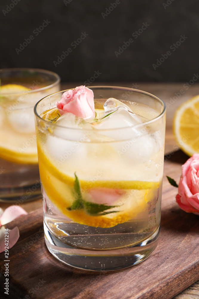 Delicious refreshing drink with lemon and roses on wooden table Delicious refreshing drink with lemon and roses on wooden table