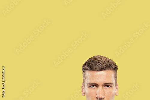 Caucasian young man's close up shot on yellow studio background. Beautiful male model with well-kept skin. Concept of human emotions, facial expression, sales, ad. Looking at camera. Copyspace.