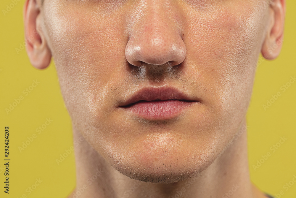 Caucasian young man's close up on yellow studio background. Beautiful male model with well-kept skin. Concept of human emotions, facial expression, sales, ad. Copyspace. Lips and cheeks.