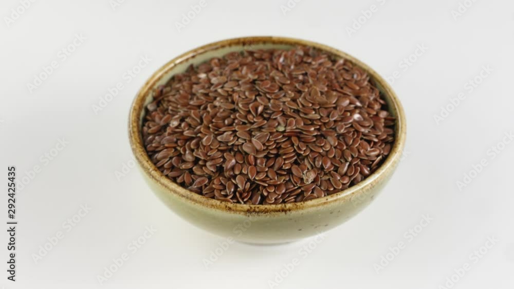Rotation flax seeds in ceramic bowl on white background. Rotation flax seeds in ceramic bowl on white background.