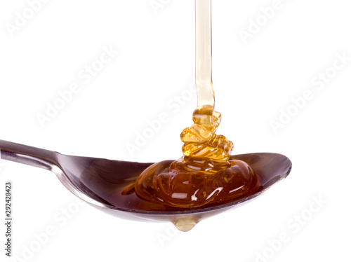 sticky honey flowing into a spoon.