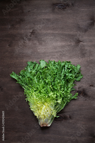 Frieze salad on a dark wooden background. Fresh greens. Place for text.