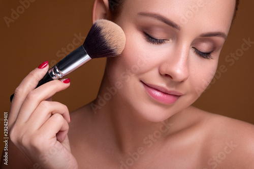 Cuadro en lienzo Caucasian brunette woman apply blush on a cheekbone with a brush