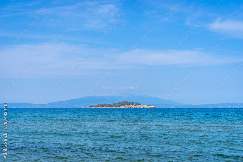 Seaside view horizon of the ocean water with an kafkanas island on the horizon in sunny day from the beach at Olympiada Greece