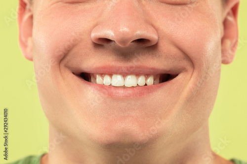 Caucasian young man's close up shot on studio background. Beautiful male model with well-kept skin. Concept of human emotions, facial expression, sales, ad. Copyspace. Lips and cheeks, smiling.