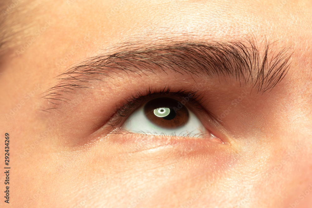 Obraz premium Caucasian young man's close up shot on studio background. Beautiful male model with well-kept skin. Concept of human emotions, facial expression, sales, ad. Copyspace. Brown eye looking at side.