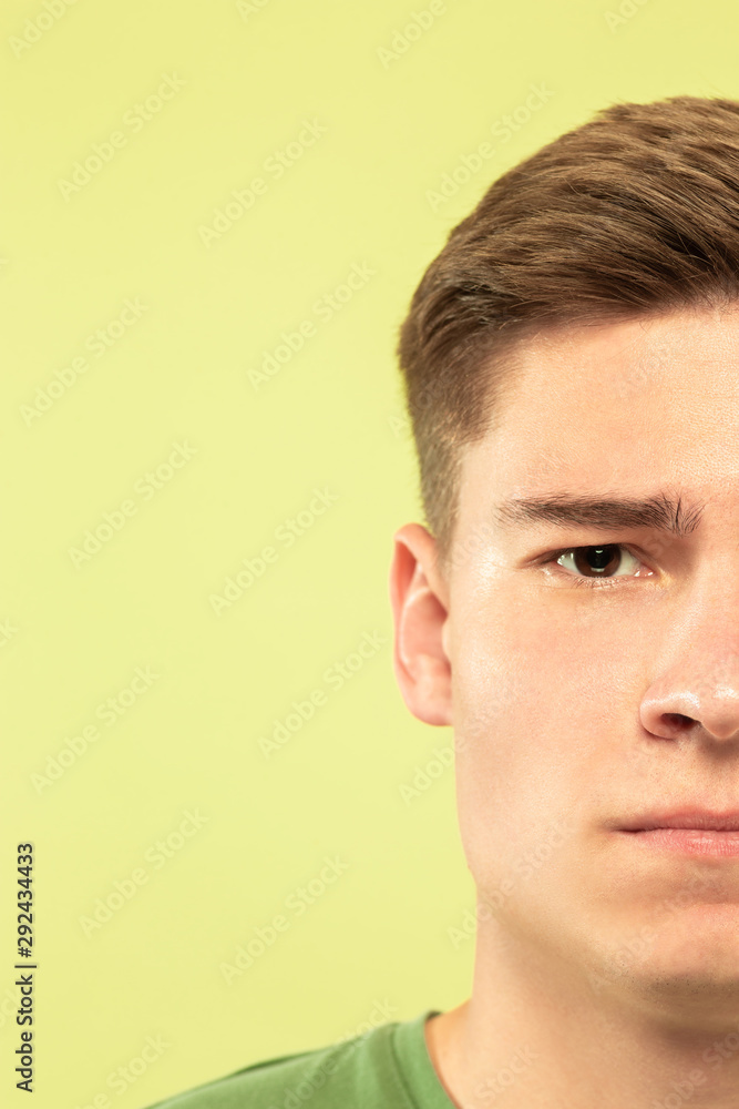 Fototapeta premium Caucasian young man's close up shot on studio background. Beautiful male model with well-kept skin. Concept of human emotions, facial expression, sales, ad. Copyspace. Sad, looking at camera.
