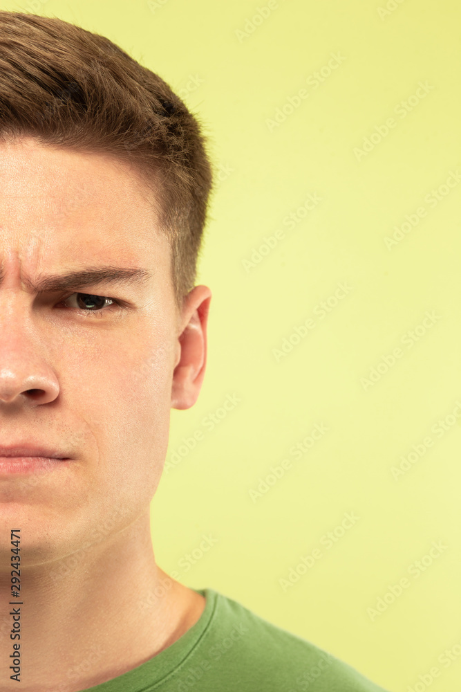 Caucasian young man's close up shot on studio background. Beautiful male model with well-kept skin. Concept of human emotions, facial expression, sales, ad. Copyspace. Angry, looking at camera. Caucasian young man's close up shot on studio background. Beautiful male model with well-kept skin. Concept of human emotions, facial expression, sales, ad. Copyspace. Angry, looking at camera.