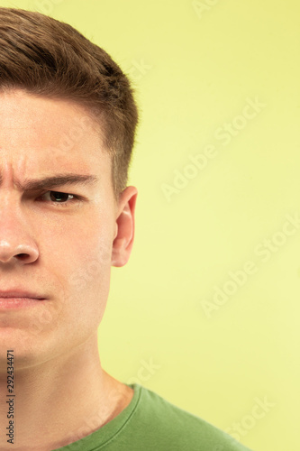 Caucasian young man's close up shot on studio background. Beautiful male model with well-kept skin. Concept of human emotions, facial expression, sales, ad. Copyspace. Angry, looking at camera.