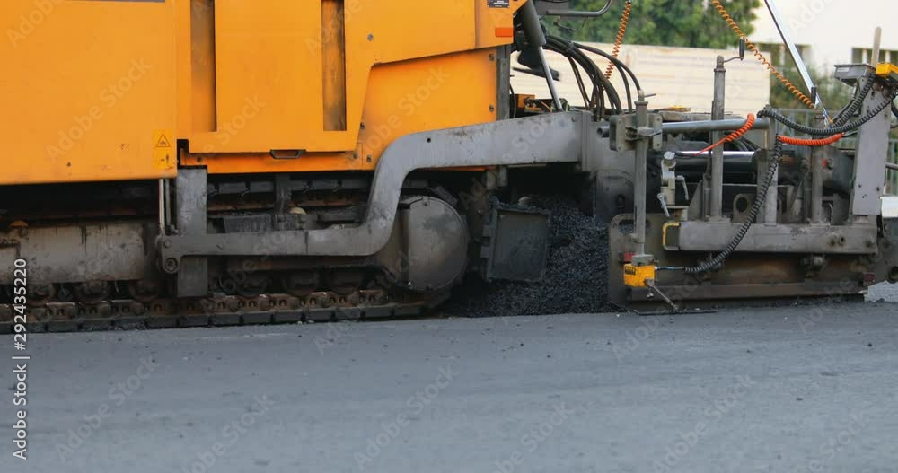 Reconstruction of the highway. Industrial pavement truck laying fresh asphalt on construction site. Road repair. Team of workers put hot asphalt on a street. Steam rising from hot asphalt surface. Reconstruction of the highway. Industrial pavement truck laying fresh asphalt on construction site. Road repair. Team of workers put hot asphalt on a street. Steam rising from hot asphalt surface.