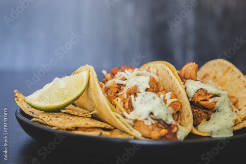 Mexican fresh chicken tacos with cabbage, cheese and cilantro cream sauce in a flour tortilla with multigrain corn tortilla chips
