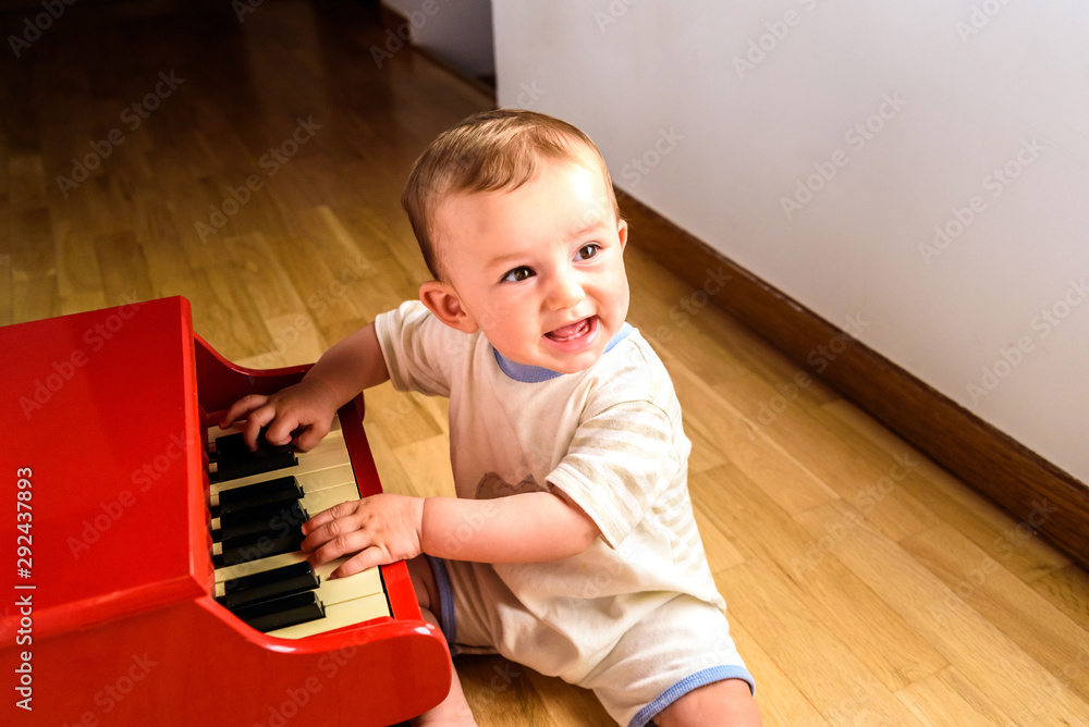 Smiling baby playing a toy piano while learning music. Smiling baby playing a toy piano while learning music.