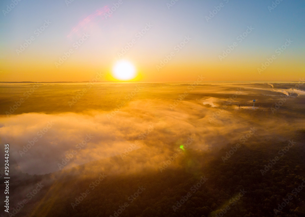 Landscape misty panorama fantastic dreamy sunrise on foggy clouds above forrest.