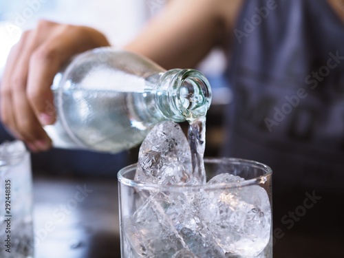 pouring water into glass, pure drinking water with ice in glass