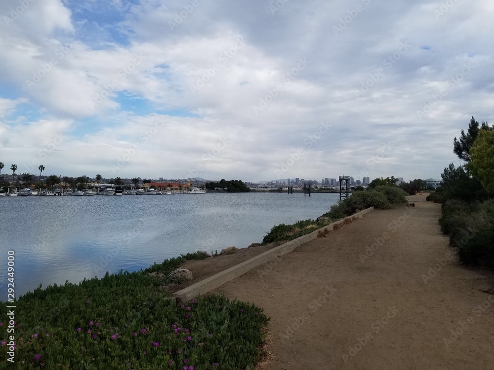 Dirt Path alongside Shoreline with City in Background