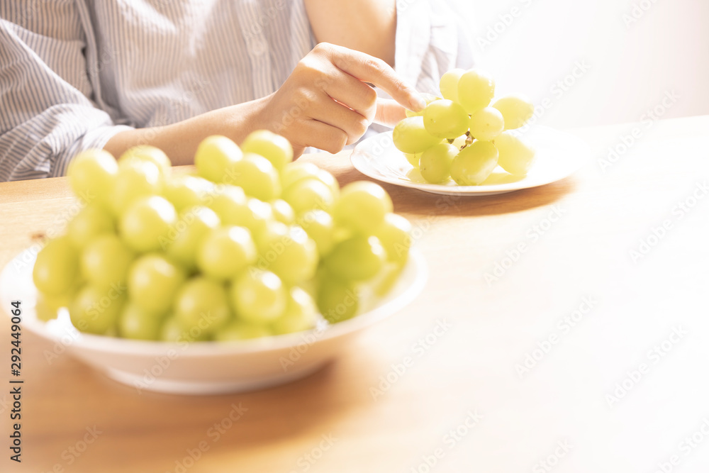 Fototapeta premium ぶどう(シャインマスカット)を食べる女性