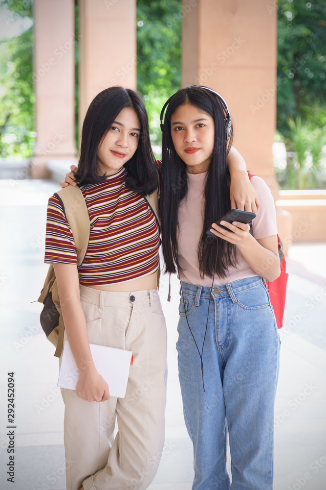 Naklejka premium Asian university students chating, talking in university campus. Female university students talking, studying and exchanging together in university campus. Education and life style concept.
