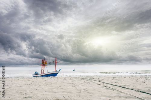 view of blue fisheries boat on a beach with cloudy sky and sea 