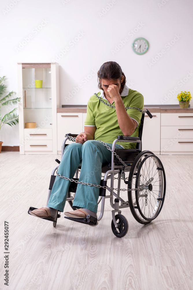 Young male invalid in wheel-chair suffering at home Young male invalid in wheel-chair suffering at home