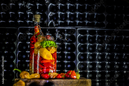 Peppers in motion ,colorful composition of peppers, chili sauce and preserved preserves in bottle and pot.