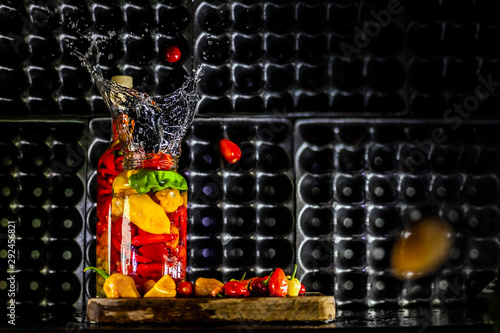 Peppers in motion ,colorful composition of peppers, chili sauce and preserved preserves in bottle and pot.