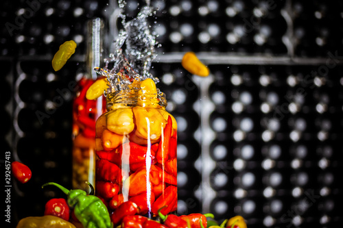 Peppers in motion ,colorful composition of peppers, chili sauce and preserved preserves in bottle and pot.