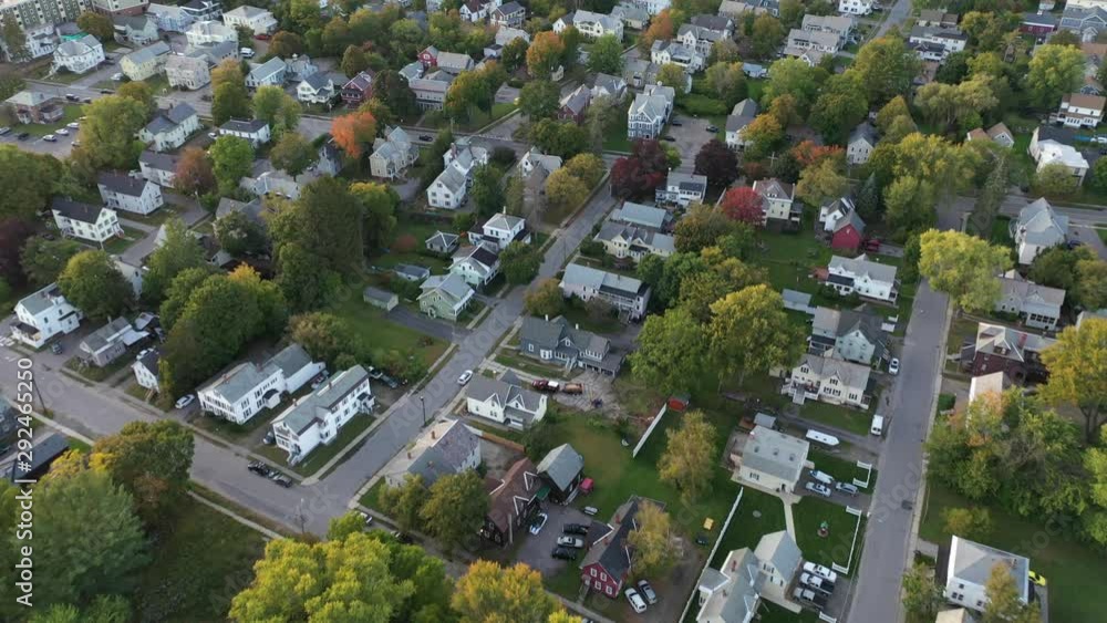 Aerial view of houses in residential neighborhood with green trees and straight streets, drone shot flying forward looking down