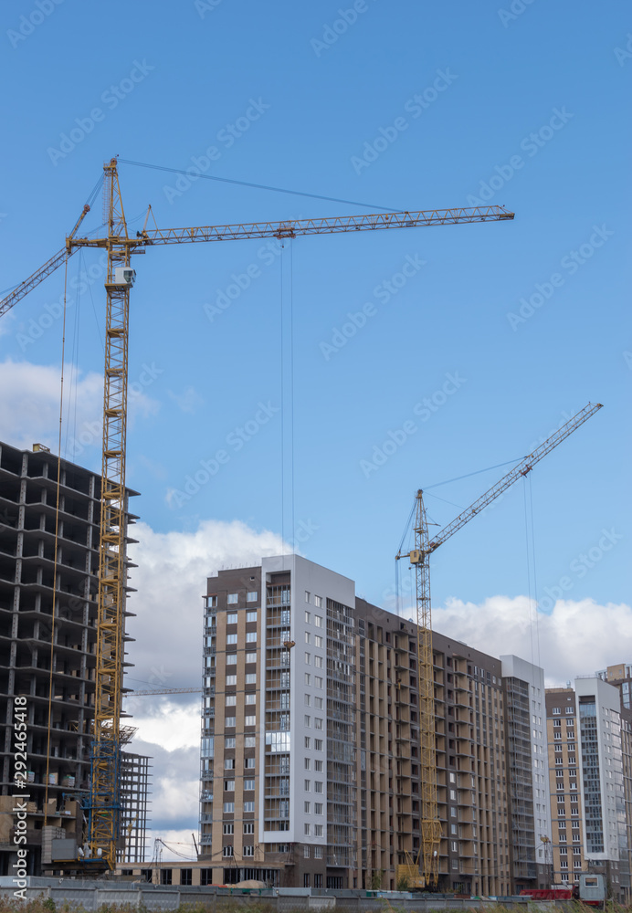 High rise building with cranes under construction. big building construction site against blue sky with white cloud. Industrial background
