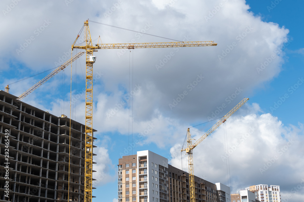 High rise building with cranes under construction. big building construction site against blue sky with white cloud. Industrial background High rise building with cranes under construction. big building construction site against blue sky with white cloud. Industrial background