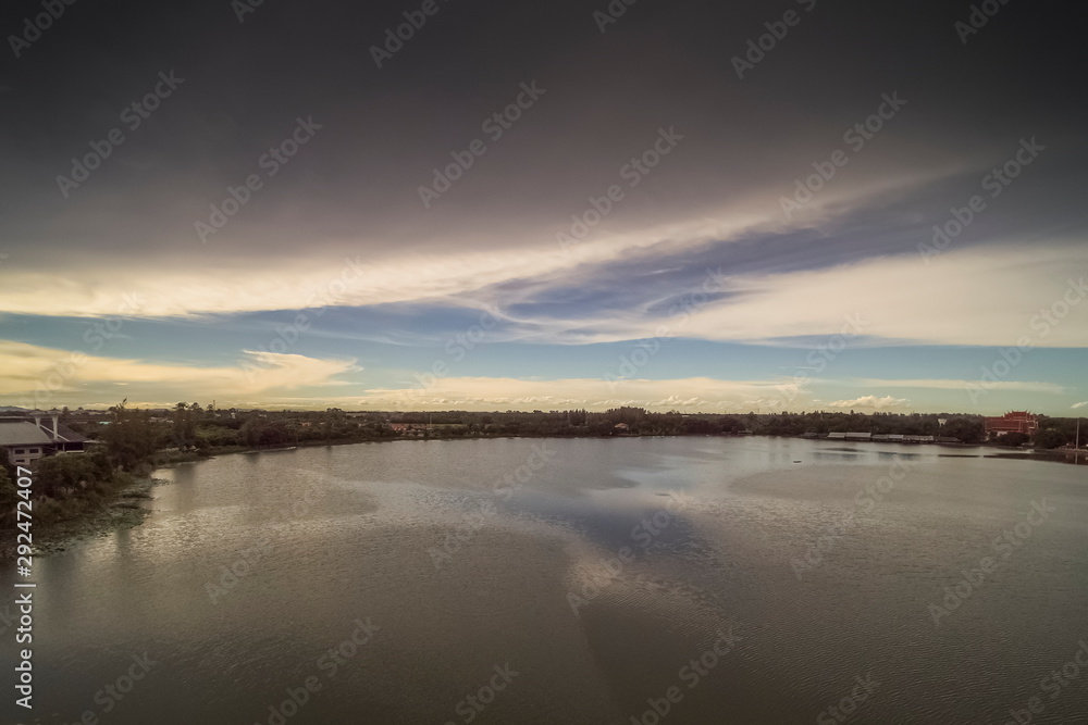 Aerial view above the lake with cloudy sky background, sunset at Krajub Reservoir with raining in Ban Pong District, Ratchaburi, Thailand.