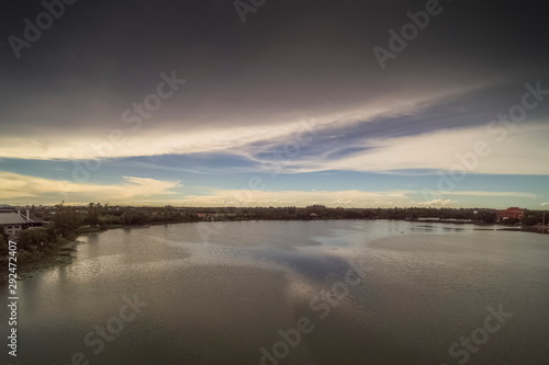 Aerial view above the lake with cloudy sky background, sunset at Krajub Reservoir with raining in Ban Pong District, Ratchaburi, Thailand.