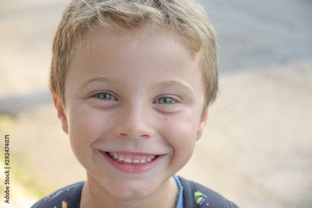 Smiling blonde kid with blue eyes going to school with his backpack Smiling blonde kid with blue eyes going to school with his backpack