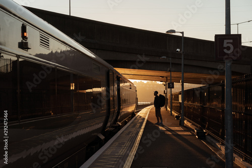 station silhouette of a tourist with a backpack who is going to take a train at sunset