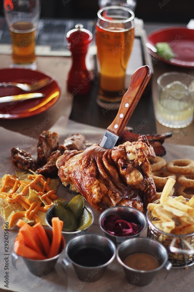 Pork knuckle with carrot, cucumber, sauce and beer on the background.