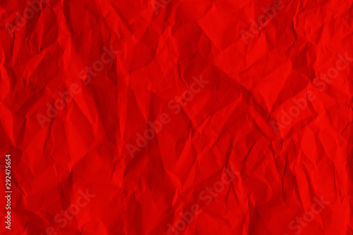 Crumpled sheet of scarlet color paper texture. Red abstract background