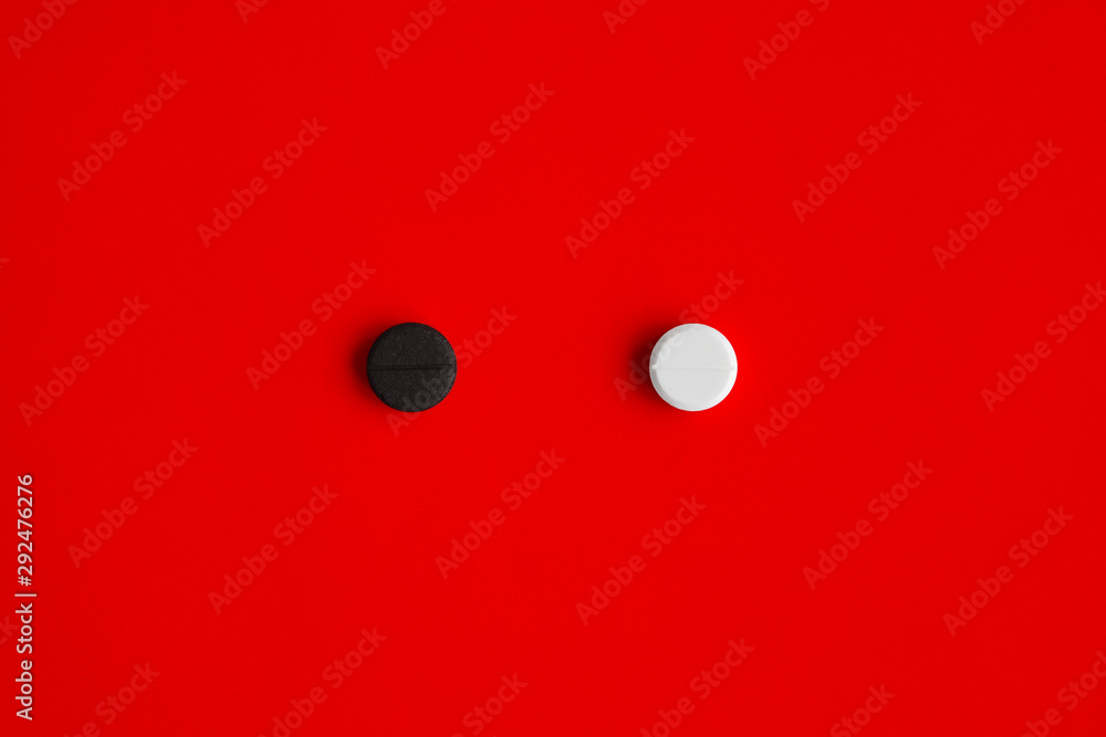 One black and one white pills on a red background. Copy space One black and one white pills on a red background. Copy space