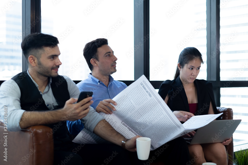 businessmans reading newspaper and talk with his team businessmans reading newspaper and talk with his team