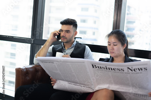 young business woman reading newspaper to update her team before meeting