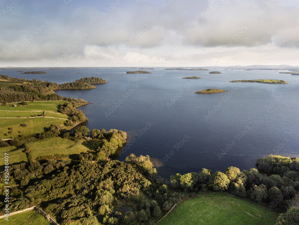 Lake Corrib, county Galway Ireland, Sunny day with cloudy blue sky and green fields separated by stone fences, islands in the lake, Aerial drone view,