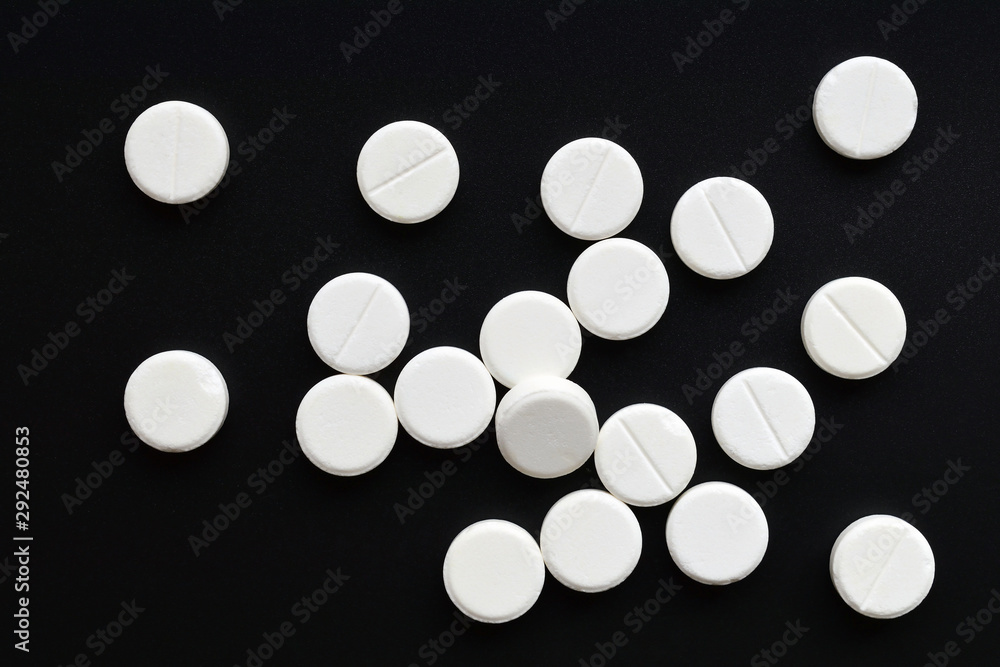 White round tablet pills placed at random on black background. Top view. Flat lay White round tablet pills placed at random on black background. Top view. Flat lay