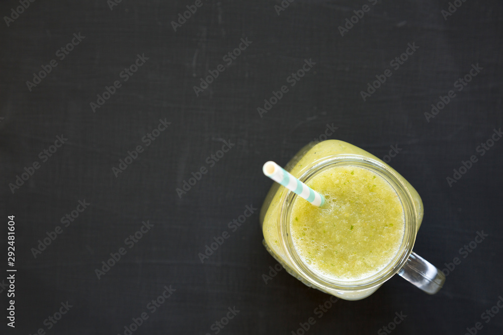 Homemade green cucumber apple smoothie in a glass jar on a black surface, top view. Flat lay, overhead, from above. Space for text. - obrazy, fototapety, plakaty 