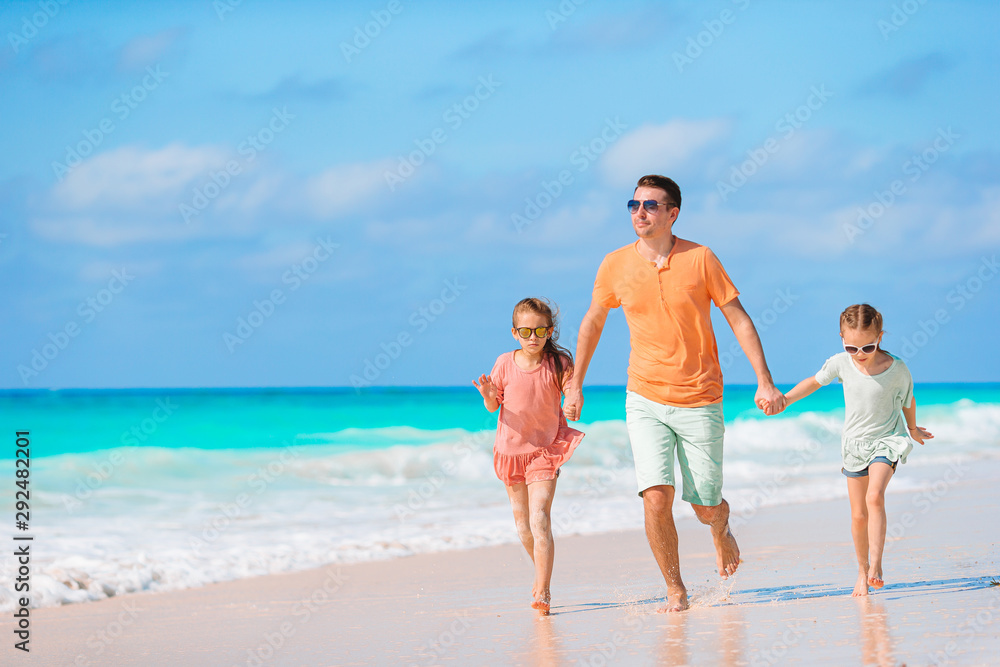 Happy beautiful family of dad and kids on white beach