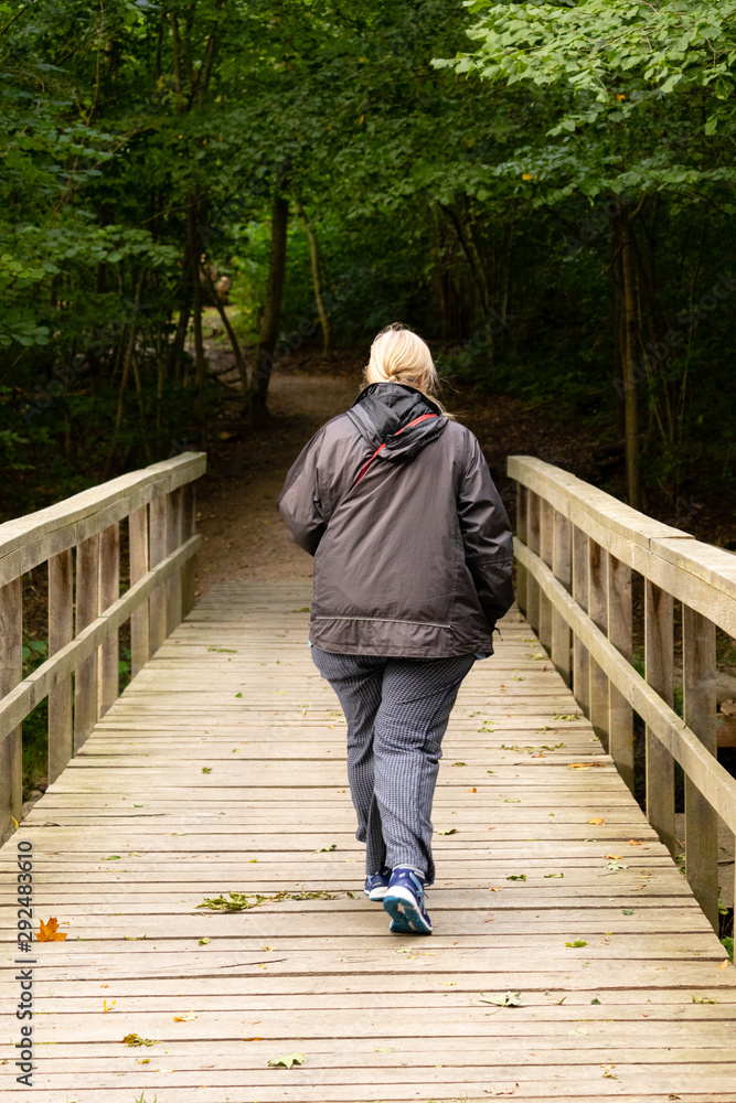 Fototapeta premium Old woman walkingover a bridge