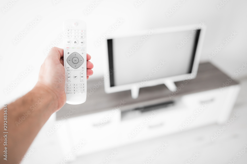 Hand holding TV remote controller with a modern television set. Hand holding TV remote controller with a modern television set.