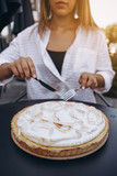 Tasty lemon meringue pie. Traditional french sweet pastry tart. female with fork and knife sits at table opposite big cake and plans to eat it completely