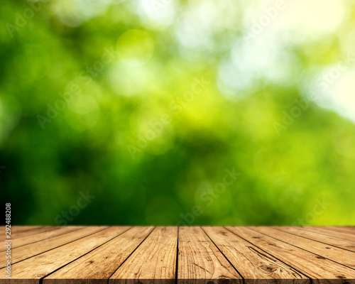 Brown wood surface on a green background. Green leaf background  blurred sun  abstract bokeh can be used for displaying or editing your product.