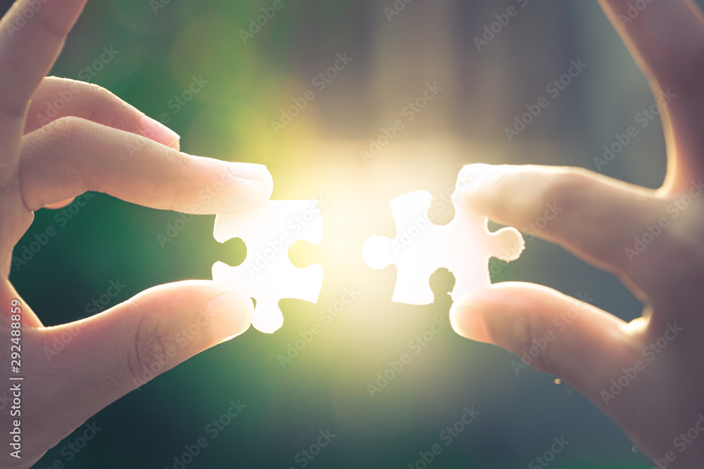 Two hands holding a jigsaw puzzle on the evening light Two hands holding a jigsaw puzzle on the evening light