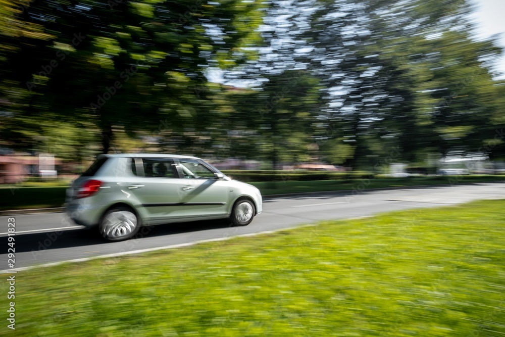 Fast driving small light green car taken with wide angle lens causing a strong motion blur effect